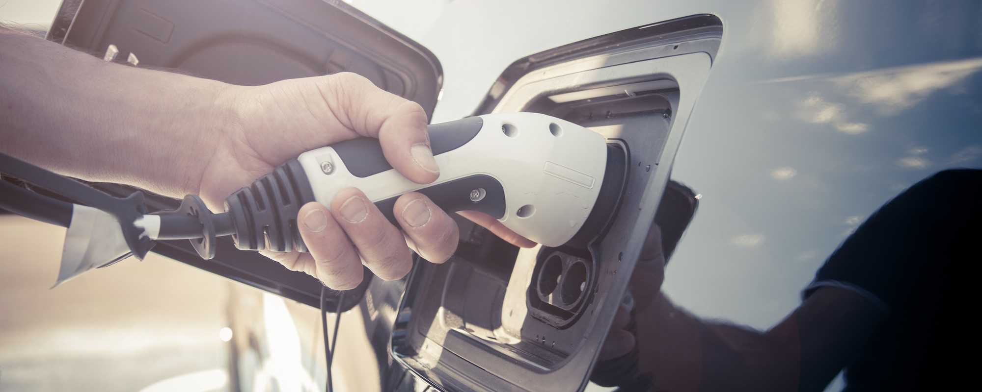 A person charging an electric vehicle, promoting clean transportation through our Drive Green program.